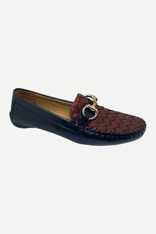 A women's loafer in dark navy blue leather with a brown woven leather strap across the instep featuring a gold-tone horsebit detail, shown against a plain light gray background.