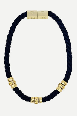 Navy blue braided cord bracelet with gold beads on a white background